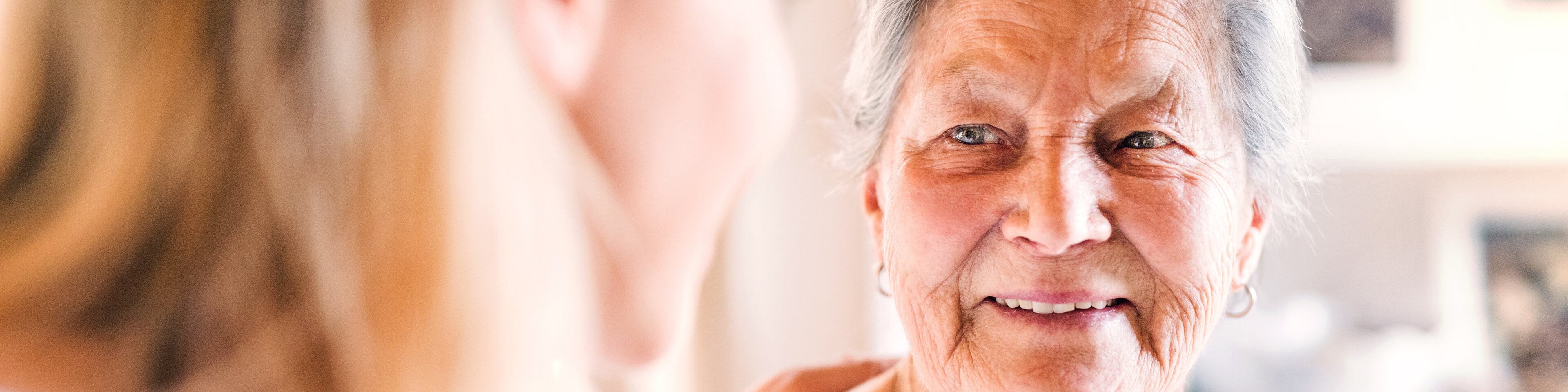 eine alte und eine junge Frau schauen sich lächelnd in die Augen | © Halfpoint - adobestock